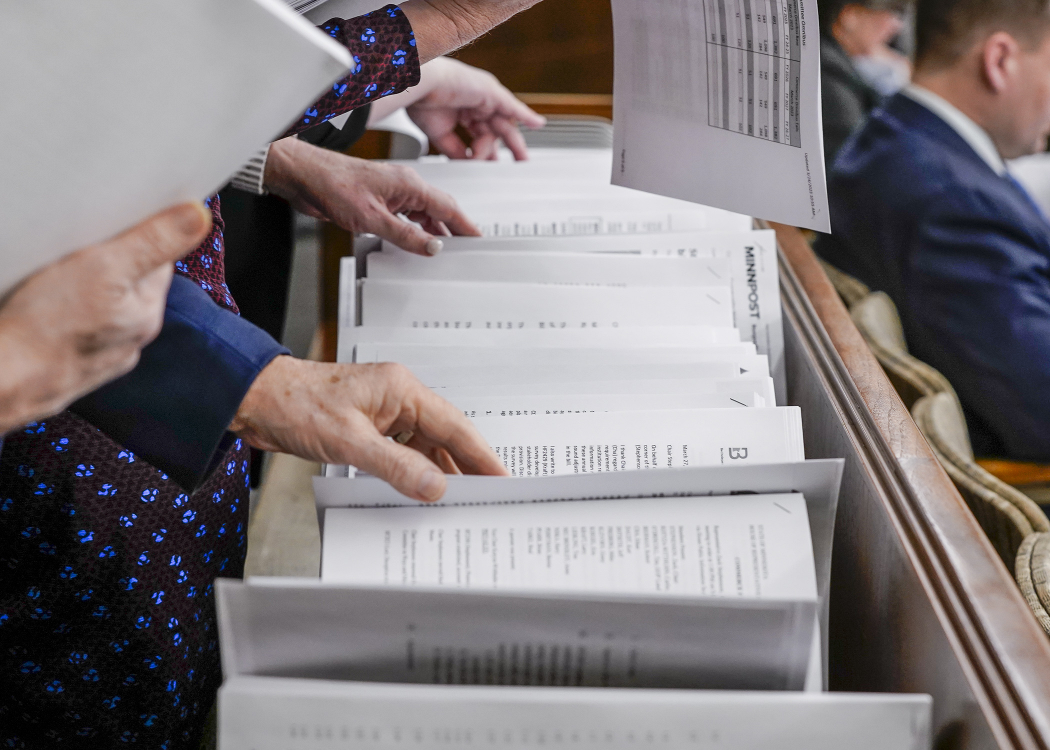 Hearing attendees jockey to grab documents relating to the omnibus veterans and military affairs finance bill before a March 27 committee meeting. (Photo by Catherine Davis)